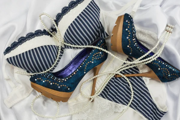 Lingerie, perline e scarpe adagiate su seta bianca — Foto Stock