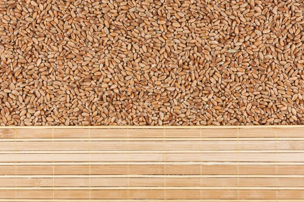 Пшеничне зерно та бамбуковий килимок — стокове фото