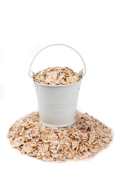 White bucket full of oat flakes, stands on a heap oat flakes — Stock Photo, Image