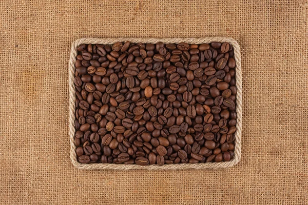 Frame made of rope with coffee beans on sackcloth, view from above — Stock Photo, Image