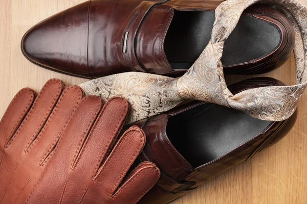 Classic mens brown shoes, tie, gloves, on wooden floor — Stock Photo, Image