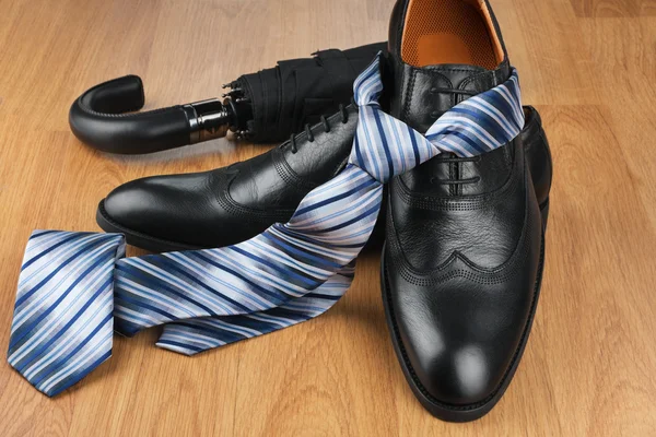 Classic mens black shoes, tie, umbrella, on wooden floor — Stock Photo, Image