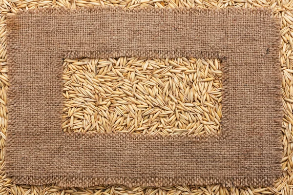 Frame made of rough burlap lies on oat grains — Stock Photo, Image