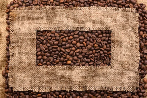 Frame made of rough burlap lies on coffee beans — Stock Photo, Image