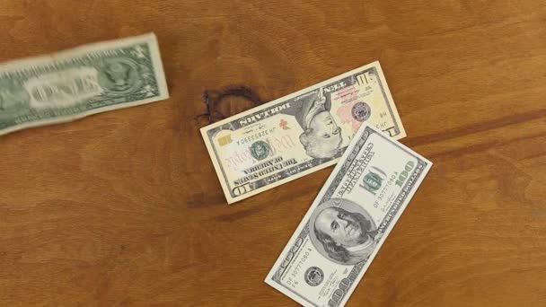 Банкноты в долларах падают к деревянному столу . — стоковое видео