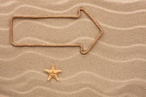 Pointer made of rope and seashell on the sand — Stock Photo, Image