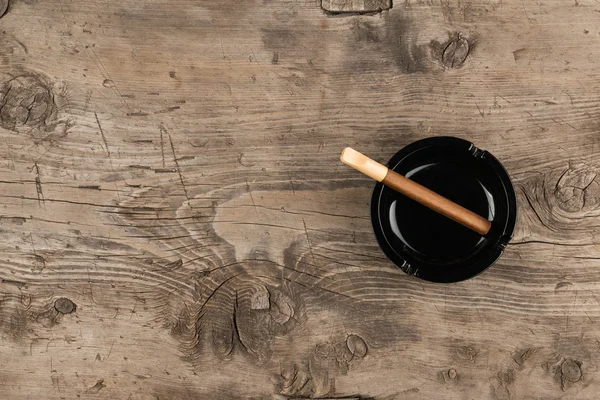 Glass ashtray with cigar stands on a wooden surface — Stock Photo, Image