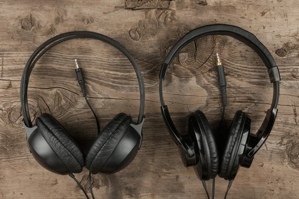 Dos auriculares y el cordón simbólico de un amor por la música sobre un fondo de textura de madera antigua — Foto de Stock