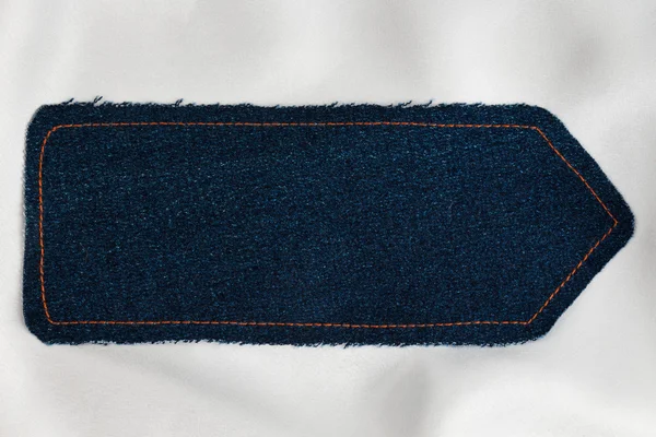 Pointer made of denim fabric with yellow stitching on white silk — Stock Photo, Image