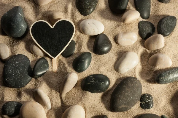 Primo piano di pietre e cuore che fuoriescono dalla sabbia al sole — Foto Stock