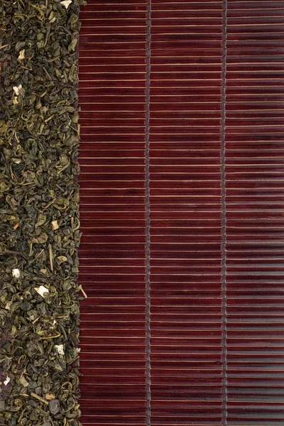 Té verde seco en una alfombra de bambú oscuro —  Fotos de Stock