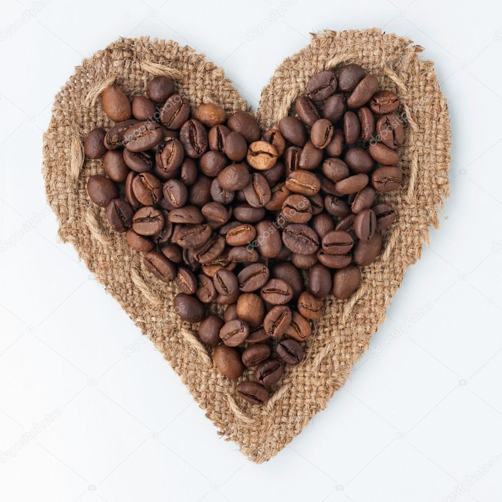 Heart of burlap and coffee beans lying on a white background