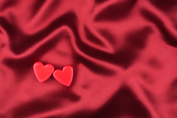 The concept of two lovers hearts lying on the red satin — Stock Photo, Image