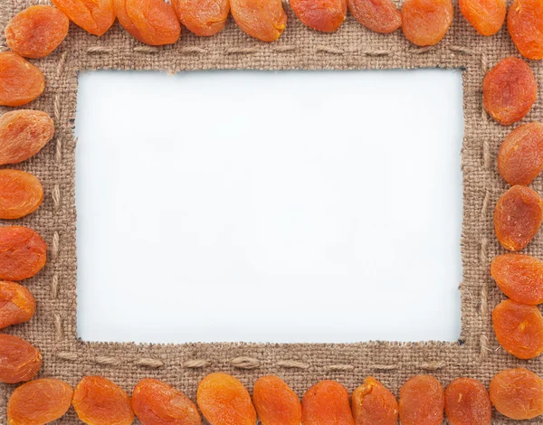 Frame made of burlap with dried apricots — Stock Photo, Image