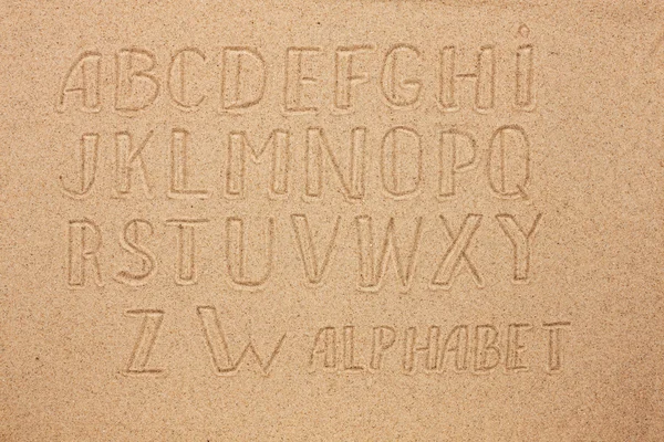 Alphabet allemand, anglais, portugais écrit sur le sable — Photo