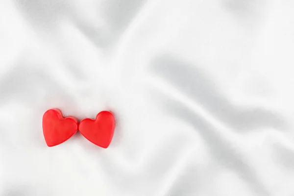 The concept of two lovers hearts lying on the white satin — Stock Photo, Image