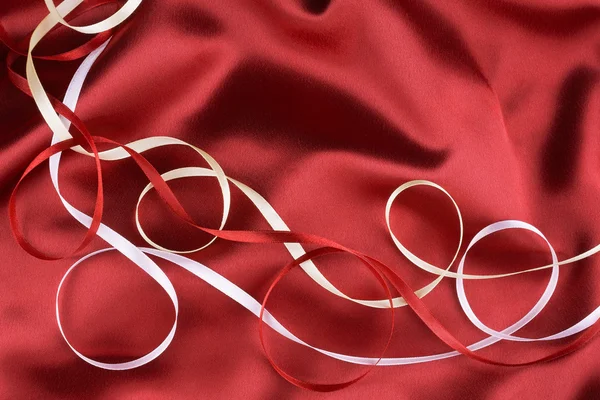 Fitas vermelhas, amarelas e brancas em uma seda vermelha — Fotografia de Stock