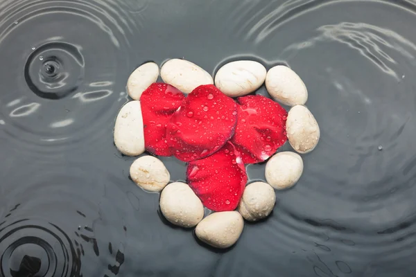 Samym symboliczne białe kamienie wśród czerwonych płatków róży — Zdjęcie stockowe