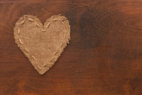 Il cuore simbolico della tela giace su una superficie di legno — Foto Stock