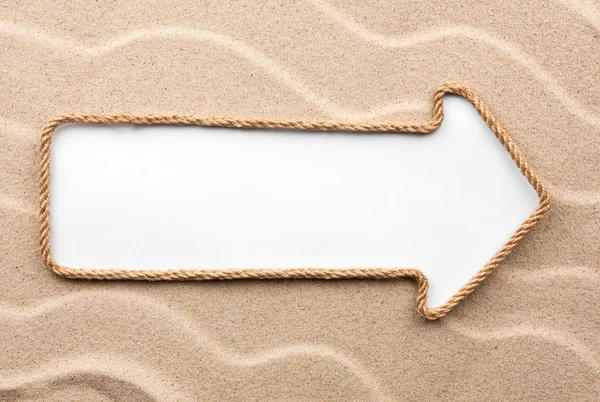 Aanwijzer gemaakt van touw met een witte achtergrond op het zand — Stockfoto