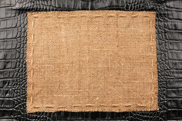 Frame of burlap, lies on a background of black leather — Stock Photo, Image