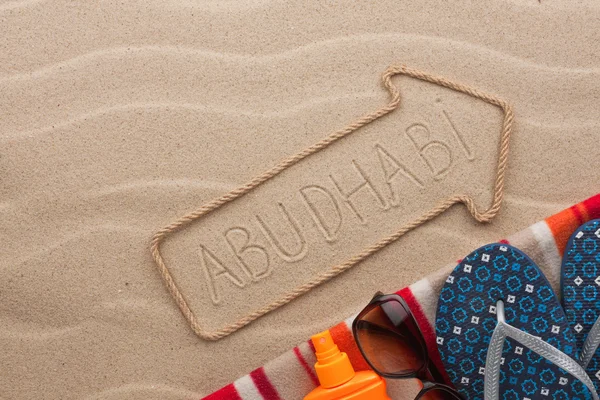 Abu Dhabi  pointer and beach accessories lying on the sand — Stock Photo, Image
