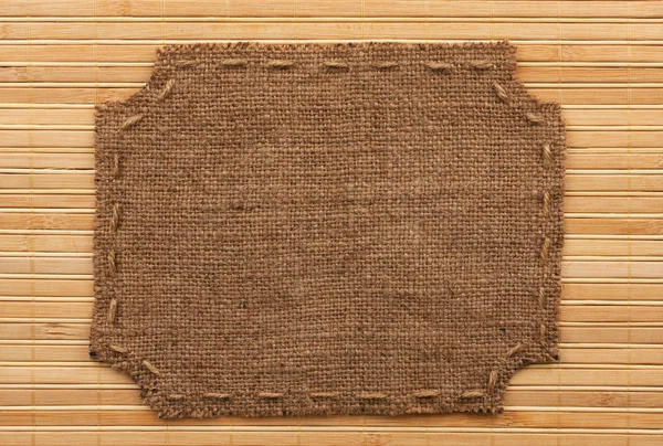 Frame of burlap, lies on a background of  bamboo mat — Stock Photo, Image