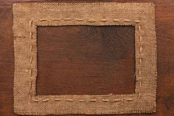 Frame of burlap, lies on a background of wood — Stock Photo, Image