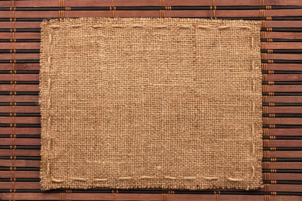 Frame of burlap, lies on a background of  bamboo mat — Stock Photo, Image