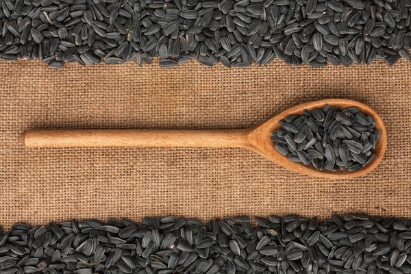 Cucchiaio di legno con semi di girasole si trova su sacco — Foto Stock