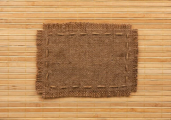 Marco de arpillera, se encuentra sobre un fondo de estera de bambú —  Fotos de Stock
