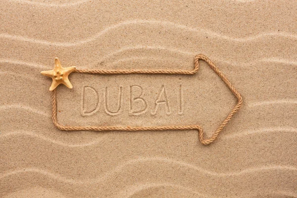 Pfeil aus Seil und Muscheln mit dem Wort dubai auf dem san — Stockfoto