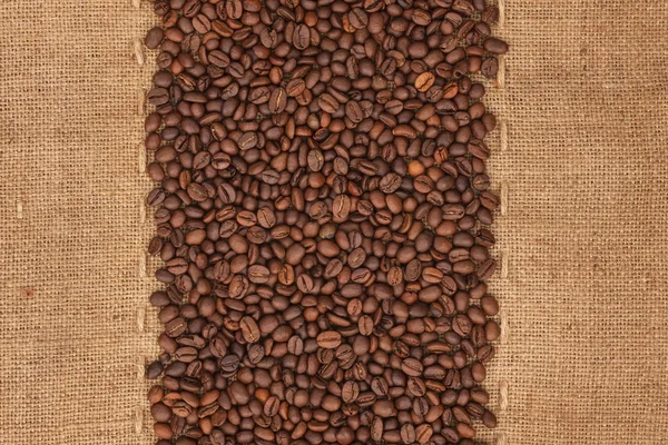 Кофейные зерна лежат на мешковине — стоковое фото