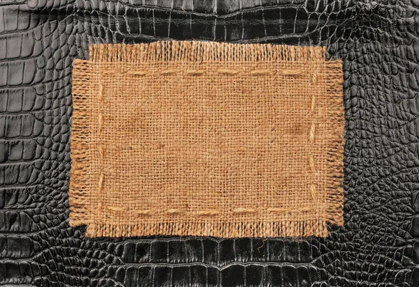 Frame of burlap, lies on a background of black leather — Stock Photo, Image