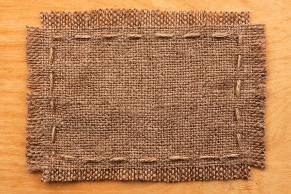 Frame of burlap, lies on a background of wood — Zdjęcie stockowe