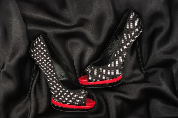 High-heeled shoes lying on black  fabric