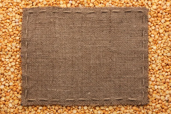 Рамка из мешковины с линией лежит на семенах гороха — стоковое фото