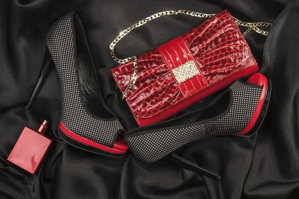 Rote Tasche, Schuhe und Parfüm auf schwarzem Satin liegend — Stockfoto