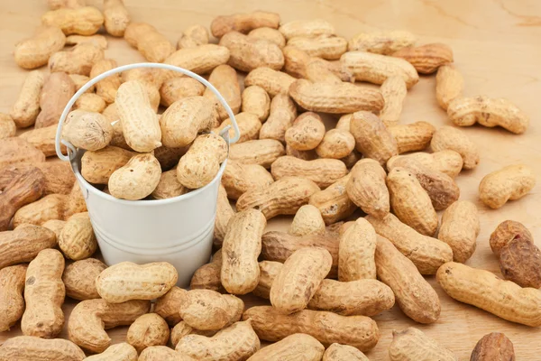 White bucket with  dried peanuts  on the wooden floor — Stock Photo, Image