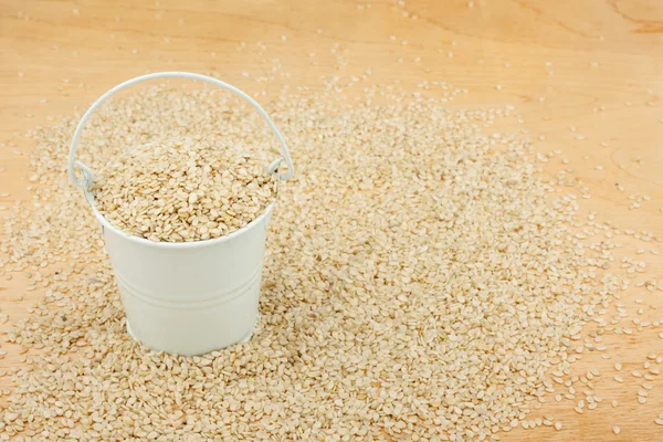 White bucket with sesame seeds  on the wooden floor — Stock Photo, Image