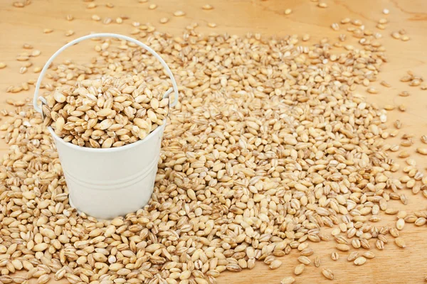 White bucket with pearl barley on the wooden floor — Stock Photo, Image