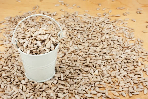 White bucket with sunflower seeds  on the wooden floor — Stock Photo, Image