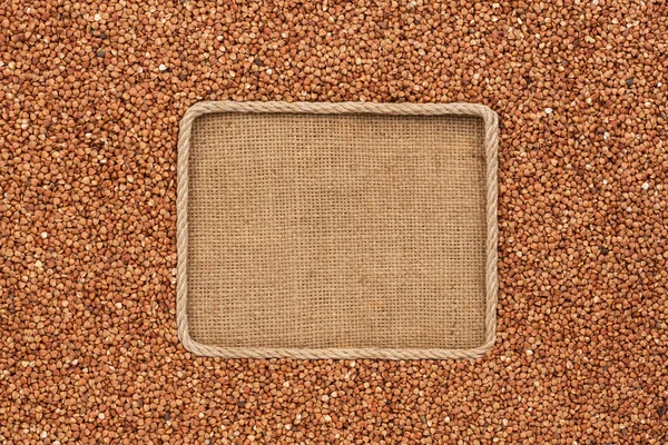 Frame made of rope with buckwheat grains  on sackcloth — Stock Photo, Image