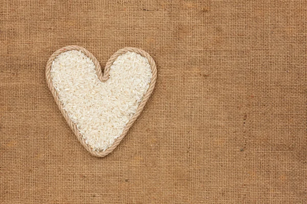 Coeur fait de corde avec des grains de riz couché sur un sac — Photo