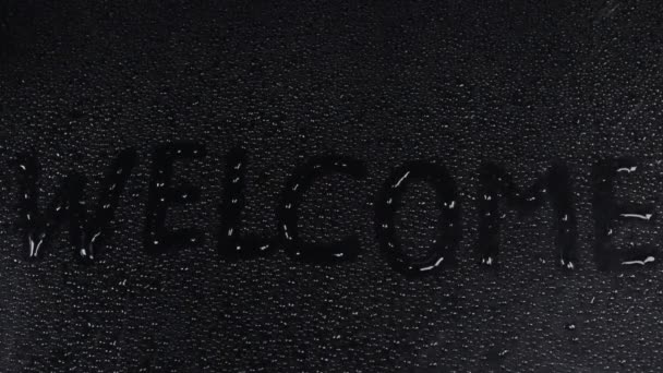 在湿的黑色背景上写手指表示欢迎 — 图库视频影像