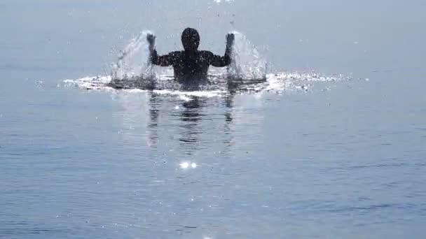 Hombre feliz en el agua en los rayos del sol, salpicaduras, alegría . — Vídeo de stock