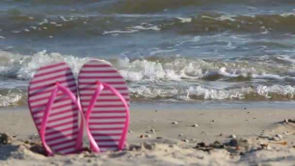 Roze flip-flops wazig, tegen de achtergrond van de golven — Stockvideo