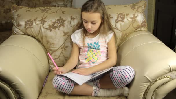 Милая девочка рисует сидя на стуле — стоковое видео