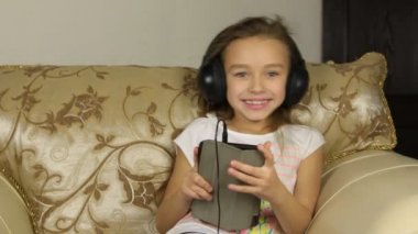 Bir tablet ile oturma ve kulaklıklar müzik dinlemek kız.