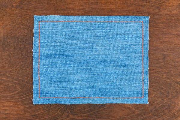 Quadro do texto de um tecido de calça azul com as linhas costuradas de um fio cor-de-laranja — Fotografia de Stock